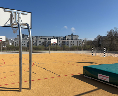 Basketballständer auf Sportplatz, rechts Hochsprungmatte